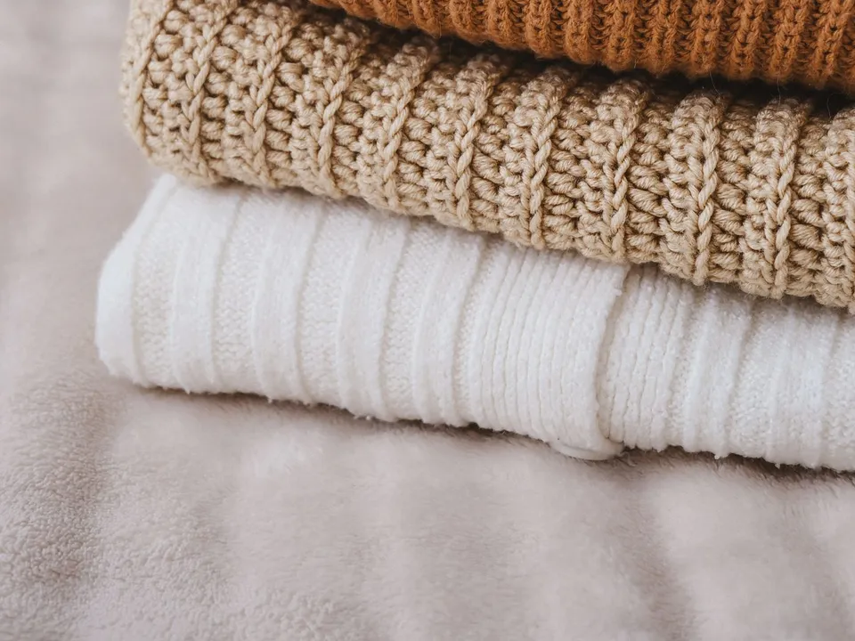 Stack of folded knitted sweaters in warm autumn colors
