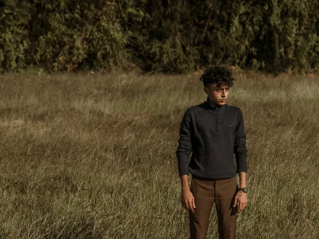 Model in a grey zipper sweater in tall grass