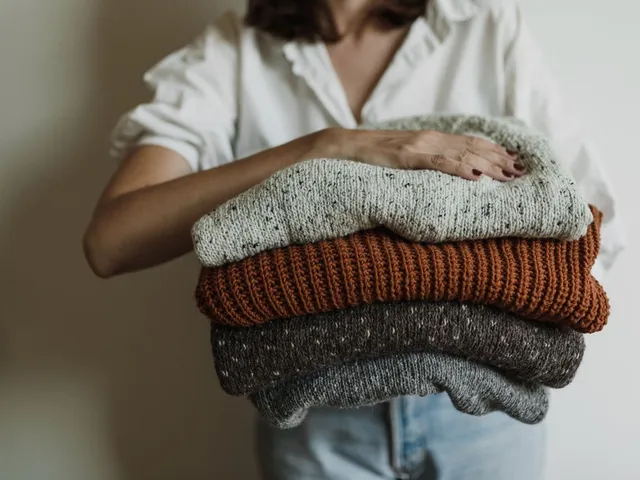 Hands holding a stack of cozy knit sweaters