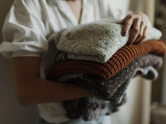 Stack of folded knit sweaters in autumn colours